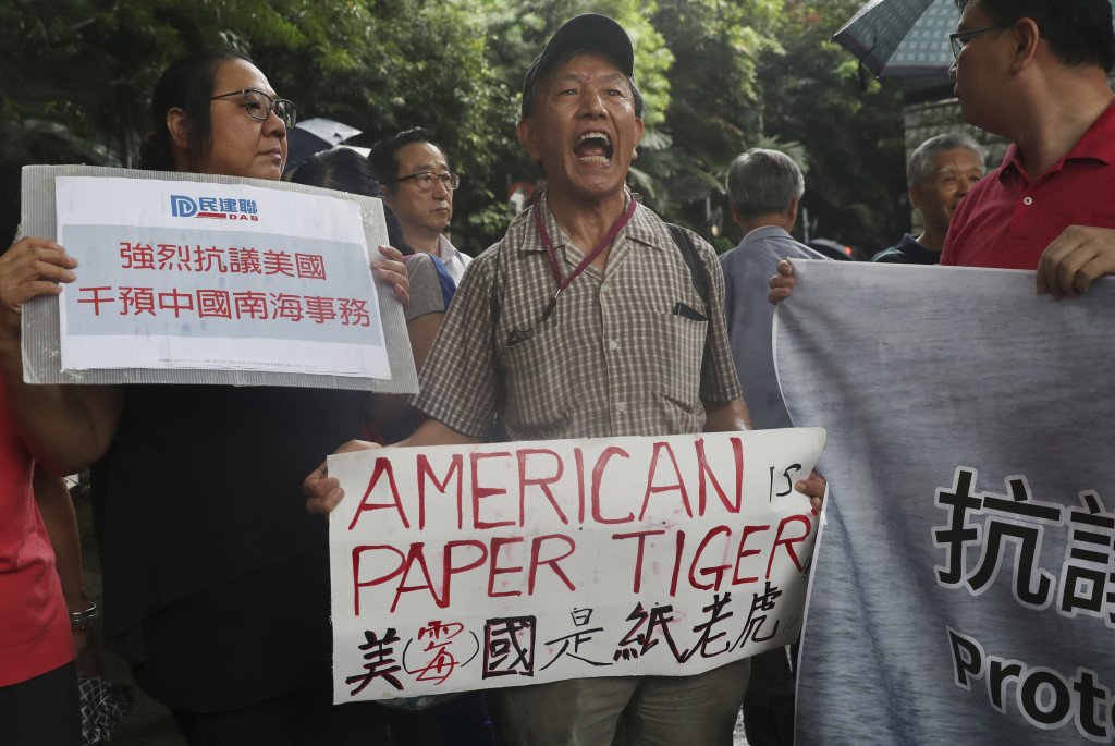 Pro-Beijing protesters shout slogans against the United States supporting an international court ruling of the South China Sea outside the U.S. Consulate in Hong Kong, Thursday, July 14, 2016. China warned other countries Wednesday against threatening its security in the South China Sea after an international tribunal handed the Philippines a victory by saying Beijing had no legal basis for its expansive claims there. A sign, left, reads "Strongly protest against U.S. intervention in South China Sea Affairs." (AP Photo/Kin Cheung)