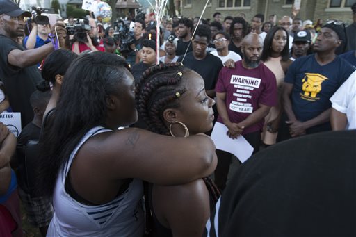Kimberly Neal (braids) is embraced at a gathering in memory of her brother where he was shot and killed in Milwaukee, Wis. , Sunday, Aug. 14, 2016.  Milwaukee Police shot and killed 23-year-old Sylville Smith near this spot on Saturday. Police in Milwaukee say a black man whose killing by police touched off arson and rock-throwing was shot by a black officer after turning toward him with a gun in his hand. (Mark Hoffman/Milwaukee Journal-Sentinel via AP)