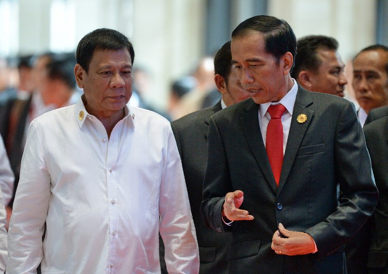 Philippine President Rodrigo Duterte (L) listens to Indonesia's President Joko Widodo while heading for a plenary session during the Association of Southeast Asian Nations (ASEAN) Summit in Vientiane on September 6, 2016. The gathering will see the 10 ASEAN members meet by themselves, then with leaders from the US, Japan, South Korea and China.  / AFP PHOTO / ROSLAN RAHMAN