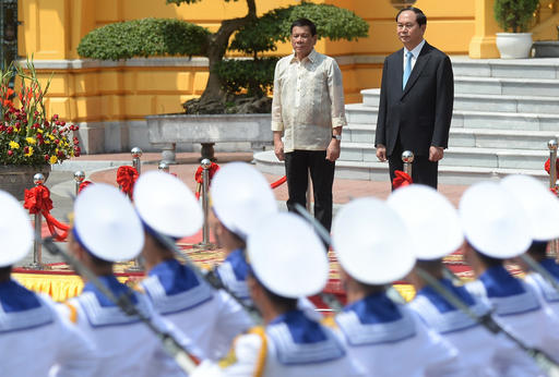 Philippine President Rodrigo Duterte, left, and his Vietnamese counterpart Tran Dai Quang stand on a podium as Vietnamese sailors from an honor guard parade during a welcoming ceremony at the presidential palace in Hanoi Thursday, Sept. 29, 2016. (Hoang Dinh Nam/Pool Photo via AP)