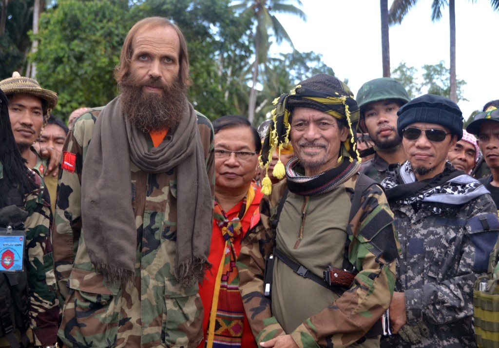 Released Norwegian hostage Kjartan Sekkingstad, front row left, poses with Moro National Liberation Front Chairman Nur Misuari, front row second right, after being turned over by ransom-seeking Abu Sayyaf extremists in Indanan township on Jolo island in southern Philippines Sunday, Sept. 18, 2016. Sekkingstad, who was kidnapped last year along with two Canadians and a Filipino, was released Saturday and was turned over Sunday to Misuari, who in turn turned him over to Presidential adviser Jesus Dureza. (AP Photo/Nickee Butlangan)