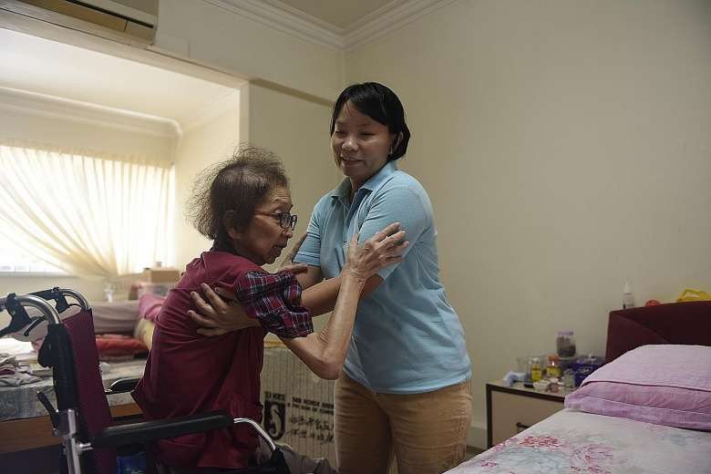 Myanmar live-in caregiver Than Than Sint helps Madam Tan Ah Sian, who has terminal gall bladder cancer, with daily activities like using the toilet. (The Straits Times/Nivash Joyvin)