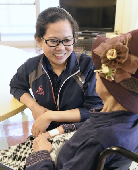 “That’s a cute hat,” Filipino care worker Marliezl Toledo tells a resident at Care Port Itabashi in Itabashi Ward, Tokyo, in early November. THE JAPAN NEWS/ASIA NEWS NETWORK