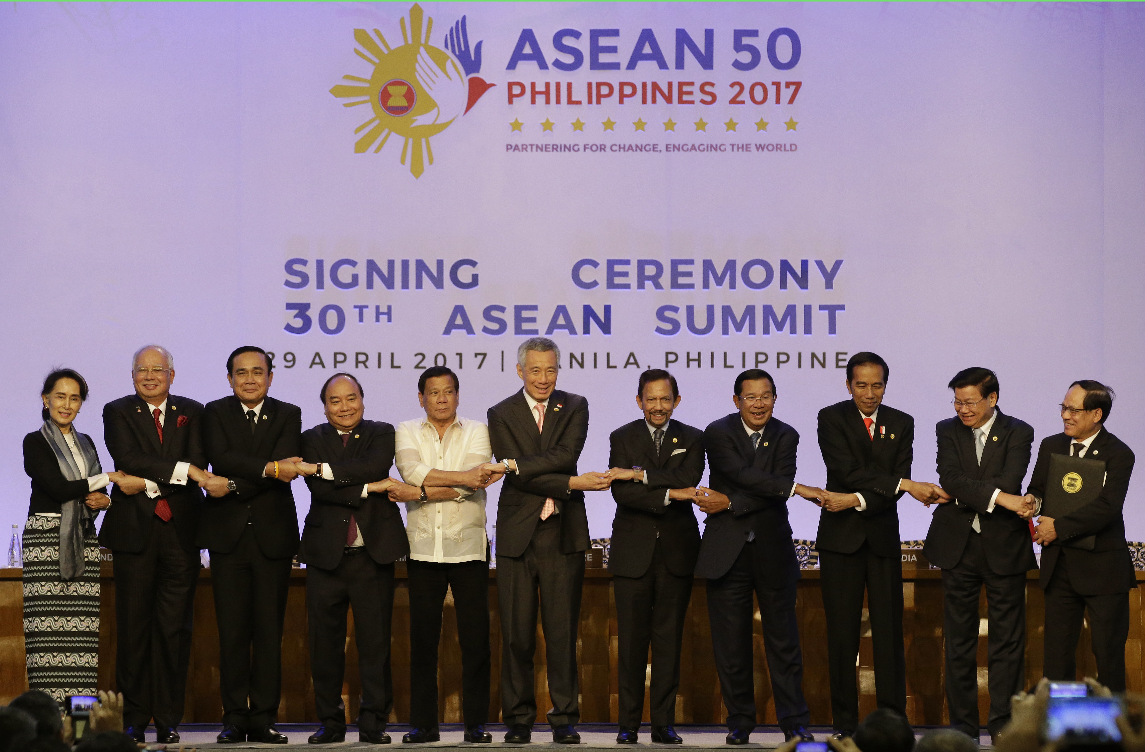 Association of Southeast Asian Nations (ASEAN) leaders from left, Myanmar Foreign Minister Aung San Suu Kyi, Malaysian Prime Minister Najib Razak,Thai Prime Minister Prayuth Chan-ocha, Vietnamese Prime Minister Nguyen Xuan Phuc, Philippine President Rodrigo Duterte, Singapore Prime Minister Lee Hsien Loong, Sultan Hassanal Bolkiah of Brunei Darussalam, Cambodian Prime Minister Hun Sen, Indonesian President Joko Widodo, Lao Prime Minister Thongloun Sisoulith and ASEAN Secretary General Le Luong Minh link arms as they pose after the signing ceremony of the 2017 ASEAN in metropolitan Manila, Philippines on Saturday, April 29, 2017. (AP Photo/Aaron Favila-POOL)