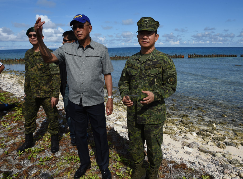 Philippine Defense Secretary Delfin Lorenzana (3L) gestures as he and military chief Eduardo Ano (R) inspect the runway of the airport during a visit to Thitu island in The Spratlys on April 21, 2017.  Philippine Defence Secretary Delfin Lorenzana flew to a disputed South China Sea island on April 21, brushing off a challenge by the Chinese military while asserting Manila's territorial claim to the strategic region. / AFP PHOTO / TED ALJIBE