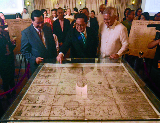 Senior Associate Justice Antonio Carpio (left) and former Foreign Secretary Albert del Rosario (right) watch as businessman Mel Velarde points to a spot on a Philippine map that is nearly 300 years old  at the launch on Thursday of Carpio’s book on the South China Sea dispute . —ARNOLD ALMACEN