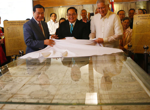 From left, Philippine Supreme Court Senior Associate Justice Antonio Carpio, Mel Velasco Velarde and former Foreign Affairs Secretary Albert Del Rosario unveil the original copy of the 1734 Murillo-Velarde Map which shows the disputed Spratlys group of islands and the Scarborough Shoal during the launching of his e-book titled "The South China Sea Dispute: Philippine Sovereign Rights and Jurisdiction in the West Philippine Sea" in the financial district of Makati city east of Manila, Philippines, Thursday, May 4, 2017. A Philippine Supreme Court justice launched a book on Thursday that questions China's historic claims to most of the South China Sea and said he will distribute it online to try to overcome China's censorship and reach its people. AP PHOTO