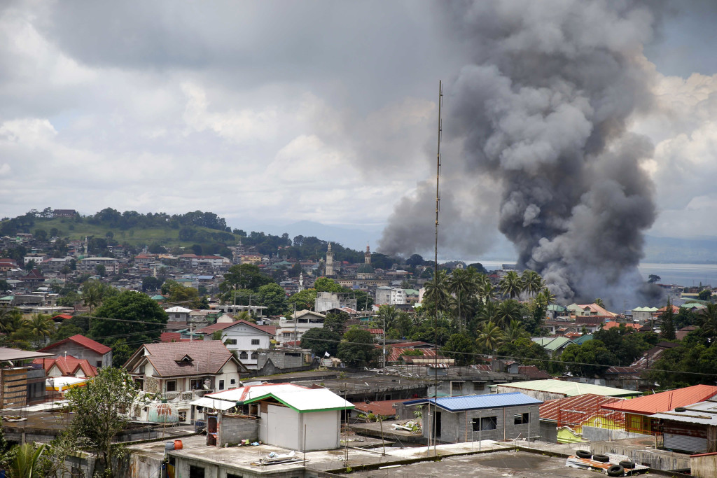 Smoke rises from houses following airstrikes by Philippine Air Force bombers as government forces battle to retake control of Marawi city from Muslim militants who lay siege for nearly a week Saturday, May 27, 2017 in southern Philippines. AP
