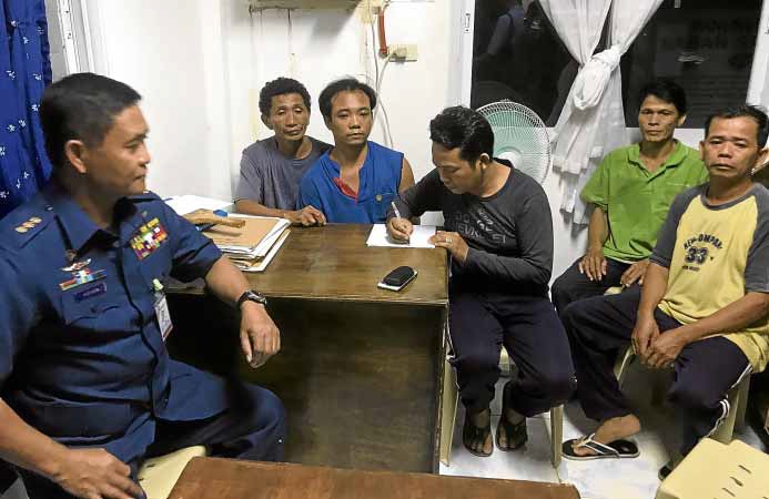 DETAINED A Coast Guard official interviews crewmembers of the Vietnamese fishing boat—Pham To, 34, captain; Pahn Lam, 34; Nguyen Thanh Chi, 49; Phan Van Liem, 41, and Nguyen Van Trong, 41—at the police station in Bolinao, Pangasinan province. —CONTRIBUTED PHOTOS