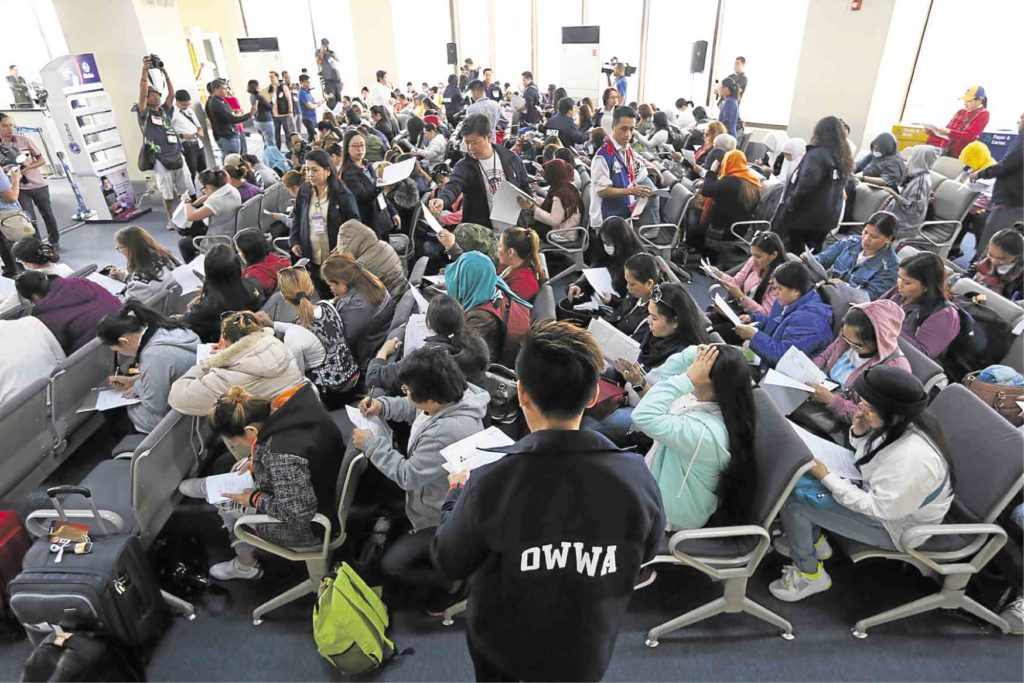 Overseas Filipino workers repatriated from Kuwait fill out information forms on their arrival at Ninoy Aquino International Airport. INQUIRER / NIÑO JESUS ORBETA
