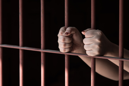 Hands of woman holding bars in jail. STORY: Pinay jailed in Singapore over blackmail try