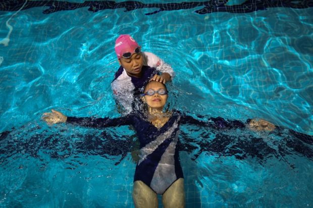 This picture taken on September 30, 2018 shows a domestic helper from the Philippines, who is also a swim instructor, providing lessons during a swimming class provided by the Splash Foundation at a swimming pool in Hong Kong. - A charity called Splash offers free swimming lessons for marginalised communities in Hong Kong including refugees. (Photo by Vivek PRAKASH / AFP) / TO GO WITH: HongKong lifestyle social sport domestic helpers, by Ayaka McGill