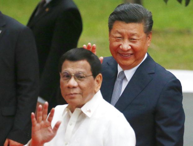 Chinese President Xi Jinping, right, and Philippine President Rodrigo Duterte wave to the media following welcome ceremony at Malacanang Palace Tuesday, Nov. 20, 2018 in Manila, Philippines. Xi is on a two-day state visit, the first in 13 years by a Chinese leader. (AP Photo/Bullit Marquez)