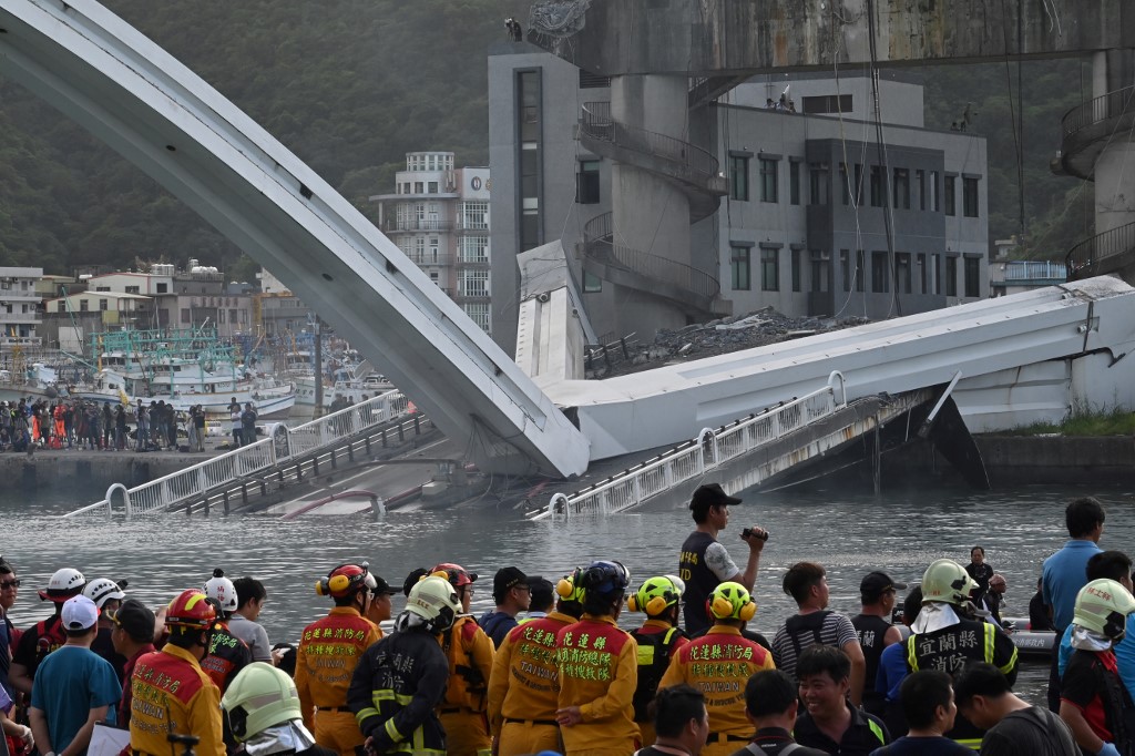 REscue personnel look on at a bridge after it collapsed in the Nanfangao fish harbour in Suao township on October 1, 2019. - The bridge collapsed in northeastern Taiwan on October 1 injuring at least 14 people as it smashed down onto fishing vessels moored underneath and sent a petrol tanker plummeting into the water. (Photo by Sam YEH / AFP)