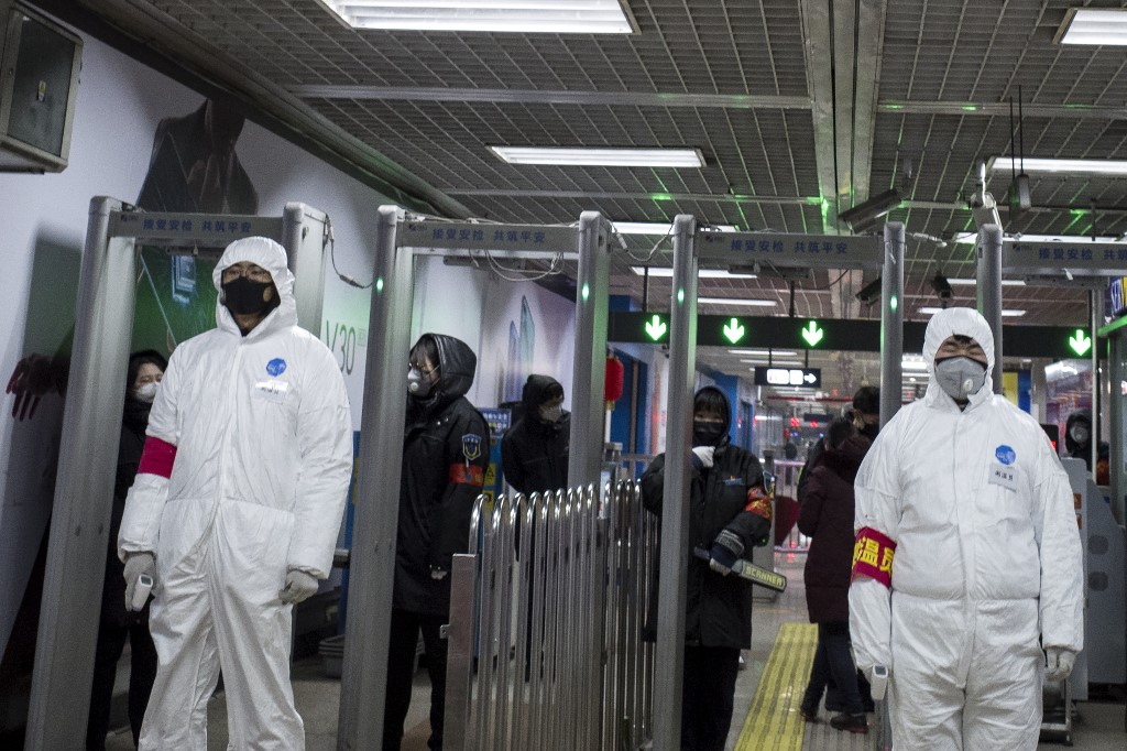 Security personnel wearing protective clothing to help stop the spread of a deadly virus which began in Wuhan, stand at a subway station in Beijing on January 26, 2020. - China on January 26 expanded drastic travel restrictions to contain a viral epidemic that has killed 56 people and infected nearly 2,000, as the United States, France and Japan prepared to evacuate their citizens from a quarantined city at the outbreak's epicentre. (Photo by NOEL CELIS / AFP)