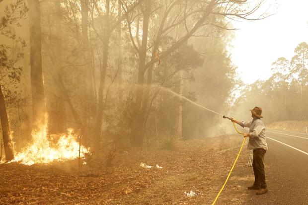 Man using water hose on wildfire in Australia