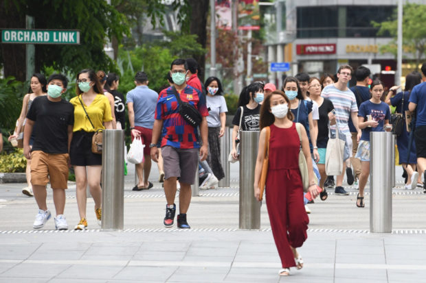 e wear facemasks to try to halt the spread of the COVID-19 coronavirus as they walk through a shopping district on Orchard Road in Singapore on April 5, 2020. Singapore will likely propose a new protocol that would allow for a cross-border movement of people once th