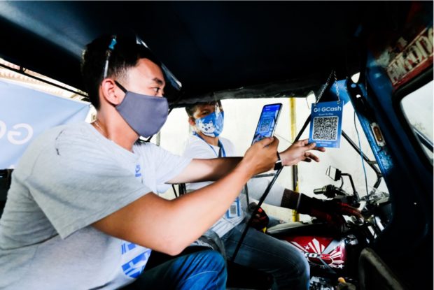 A tricycle passenger scanning the GCash QR for cashless payment