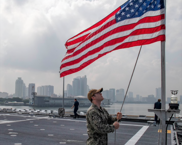 Culinary Specialist 3rd Class Matthew Deluca, from Cincinnati, raises the American flag during a sea and anchor detail aboard Independence-variant littoral combat ship USS Charleston (LCS 18)
