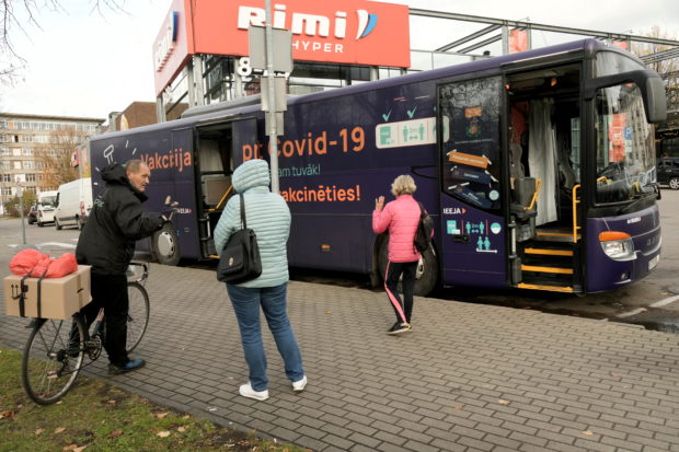 People wait to get inside a mobile coronavirus disease (COVID-19) vaccination bus next to the shopping center in Riga