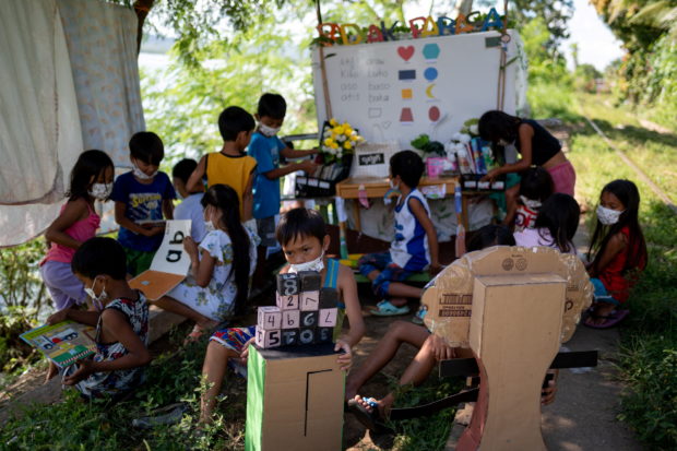 Children read and learn through the makeshift trolley which serves as a mobile library, near the railroad, in Tagkawayan, Quezon Province, Philippines, February 15, 2022. Picture taken February 15, 2022. REUTERS/Lisa Marie David