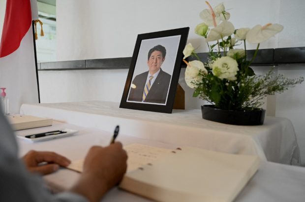 A Japanese national signs the condolence book for the late former Japanese prime minister Shinzo Abe at Japan's embassy in Manila on July 11, 2022. (Photo by JAM STA ROSA / AFP)