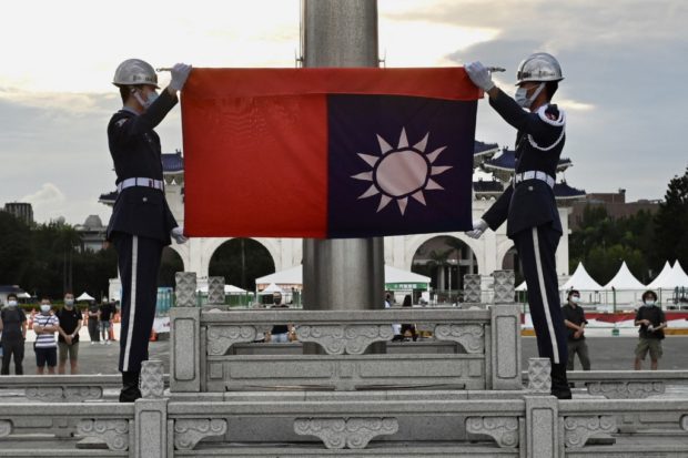 Honor guards fold the Taiwan flag during a flag lowering ceremony at the Chiang Kai-shek Memorial Hall in Taipei on June 4, 2022. (Photo by Sam Yeh / AFP)