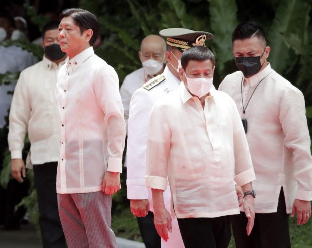 Incoming Philippine President Ferdinand Marcos Jr (L) and outgoing President Rodrigo Duterte (C) take part in the inauguration ceremony for Marcos at the Malacanang presidential palace grounds in Manila on June 30, 2022. - The son of the Philippines' late dictator Ferdinand Marcos was to be sworn in as president on June 30, completing a decades-long effort to restore the clan to the country's highest office. (Photo by Francis R. MALASIG / POOL / AFP)