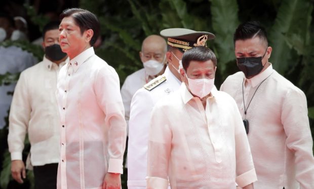Incoming Philippine President Ferdinand Marcos Jr (L) and outgoing President Rodrigo Duterte (C) take part in the inauguration ceremony for Marcos at the Malacanang presidential palace grounds in Manila on June 30, 2022. - The son of the Philippines' late dictator Ferdinand Marcos was to be sworn in as president on June 30, completing a decades-long effort to restore the clan to the country's highest office. (Photo by Francis R. MALASIG / POOL / AFP)