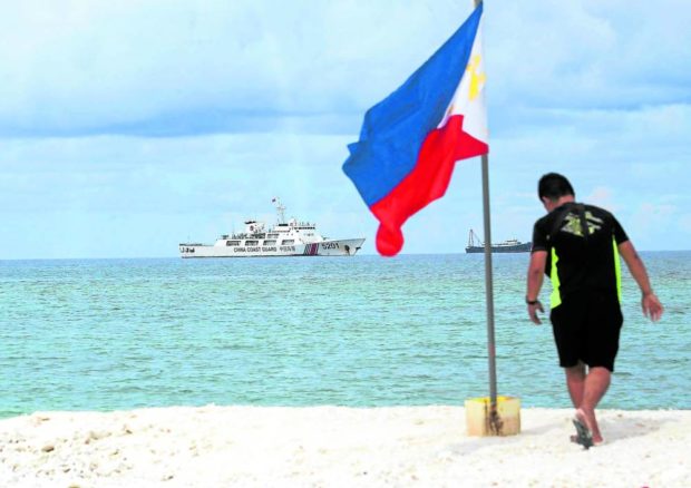 A Navy sailor plants a Philippine flag on Sandy Cay during a visit on June 26, 2022
