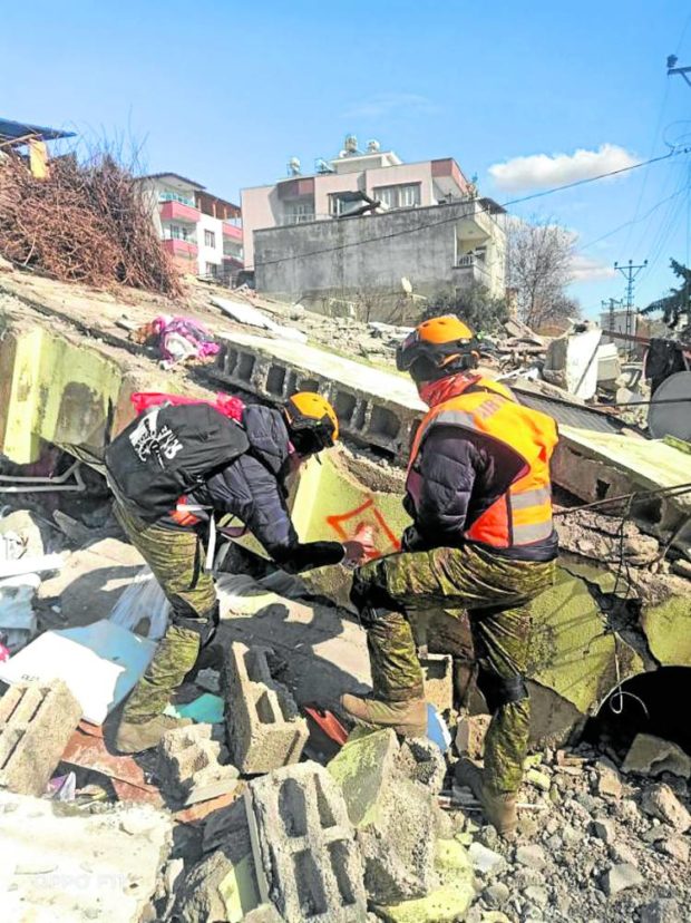 Two members of the Filipino search and rescue contingent do a sweep of a building that collapsed in the city of Adiyaman in southeastern Turkey