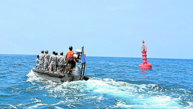 ‘BOOSTING OUR PRESENCE’ Members of Task Force Kaligtasan sa Karagatan of the Philippine Coast Guard on Saturday inspect the waters of Pag-asa (Thitu) Island in the West Philippine Sea where two buoys, one of them shown in photo, were installed last year. —FRANCES MANGOSING