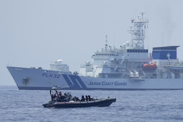 A Philippine Coast Guard rigid hull inflatable boat passes by the Japanese Coast Guard Akitsushima (PLH-32) during a trilateral Coast Guard drill of the US, Japan, and Philippines, near the waters of the disputed South China See in Bataan province, Philippines, Tuesday, June 6, 2023. 
