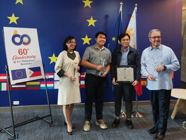 Luc Veron, EU Ambassador to the Philippines (far right), and DFA Assistant Secretary Ma Elena Algabre extend their congratulations to Julie Ar Sibala, Winner, and Eric Michael Opena, Second Runner-Up, during the unveiling and presentation of the winning logo commemorating 60 years of EU-PH relations.