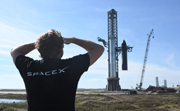 A person looks on as SpaceX's huge Super Heavy-Starship is unstacked from the booster as it sits on the launchpad at Starbase in Boca Chica, Texas, on November 16, 2023, ahead of its second test flight posponed to November 18. The US Federal Aviation Administration (FAA) on November 15, 2023 authorized SpaceX to carry out its second launch of Starship, the most powerful rocket ever built, after a first attempt in April ended in a spectacular explosion. (Photo by TIMOTHY A. CLARY / AFP)