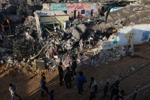 People stand amid the rubble school hit during an Israeli strike before the start of a four-day truce in the battles between Israel and Hamas militants, in Rafah in the southern Gaza Strip on November 24, 2023. A four-day truce in the Israel-Hamas war began on November 24, with hostages set to be released in exchange for prisoners in the first major reprieve in seven weeks of war that have claimed thousands of lives.Mohammed ABED / AFP
