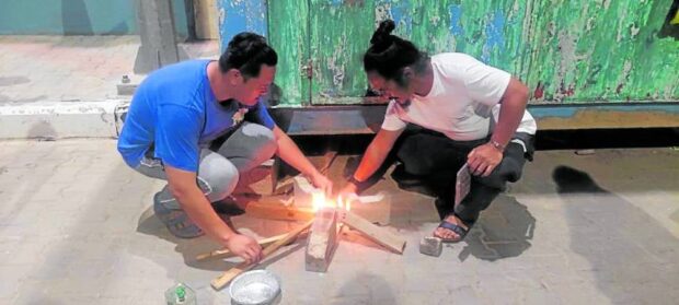 SURVIVAL MODE Filipino nurses Darwin dela Cruz and Regidor Esguerra build a fire for cooking as they make do with scant food, water and other supplies while awaiting evacuation from the Gaza Strip. —Photo from Médecins Sans Frontières