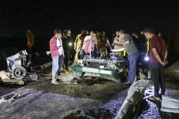 People gather around a car wreck following a car bomb blast in northern Syria's Shawa town, near the border with Turkey, on July 9, 2023. Car bombs killed at least eight people including three children in two separate incidents on July 9 in northern Syria, a war monitor said.Bakr ALKASEM / AFP