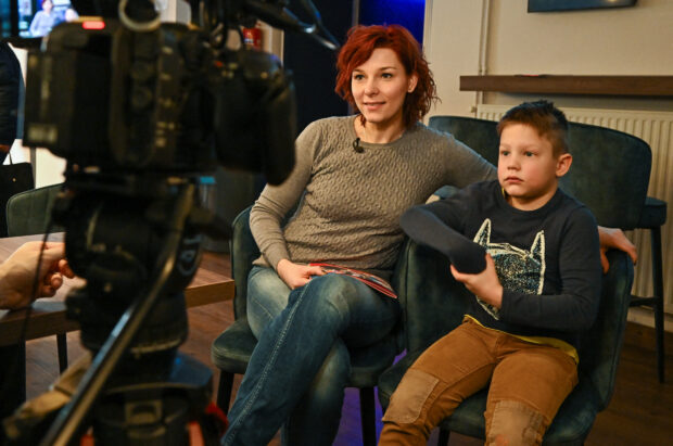 Beata Hajdu-Toth (L), incident manager and her child Matyas give an interview for AFP after a movie programme in Budapest on February 18, 2024, as the Hungarian 'Diafilmgyarto' celebrates its 70th anniversary with various events including monthly screenings of slide films at a Budapest cinema attracting dozens of children and nostalgic adults. A century-old storytelling medium, its Hungarian producer has seen a resurgence in demand for filmstrips since the 2000s as enthusiasts appreciate the chance for slower, more intimate storytelling in the age of increasingly fast-paced entertainment. Filmstrips -- sometimes called slide films -- are printed on rolls of film, but unlike traditional movies, images can be shown for any amount of time, and are not meant to create the illusion of motion. (Photo by ATTILA KISBENEDEK / AFP) / TO GO WITH AFP STORY by Andras ROSTOVANYI