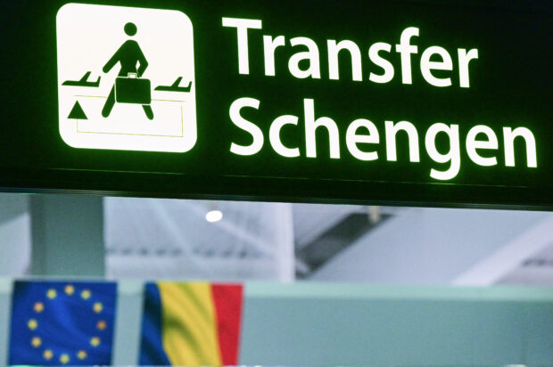 A newly installed sign pointing to Schengen transfer flights is pictured next to EU and Romanian flags, after Romania's official entry into the European area of free circulation at Otopeni's "Henri Coanda" international airport on March 31, 2024. Bulgaria and Romania joined Europe's vast Schengen area of free movement on March 31, opening up travel by air and sea without border checks after a 13-year wait. A veto by Austria however means the new status will not apply to land routes, after Vienna expressed concerns over a potential influx of asylum seekers. Despite the partial membership, the lifting of controls at the two countries' air and sea borders is of significant symbolic value. (Photo by Daniel MIHAILESCU / AFP)