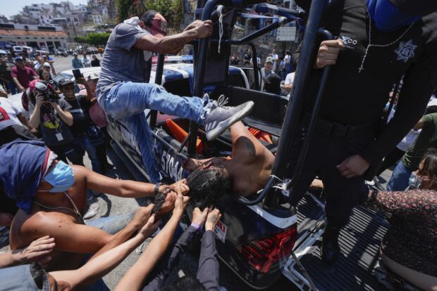 PHOTO: A woman suspected in the kidnapping and killing of an 8-year-old girl, is dragged out of a police vehicle by a mob in Taxco, Mexico, Thursday, March 28, 2024. STORY: Mob in Mexico brutally beats suspected kidnapper to death