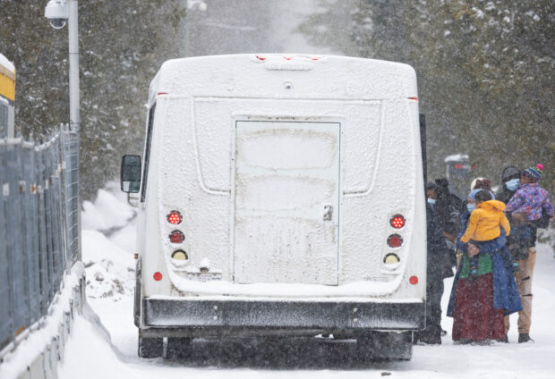 Asylum seekers board a bus after crossing into Canada from Roxham Road in Champlain New York