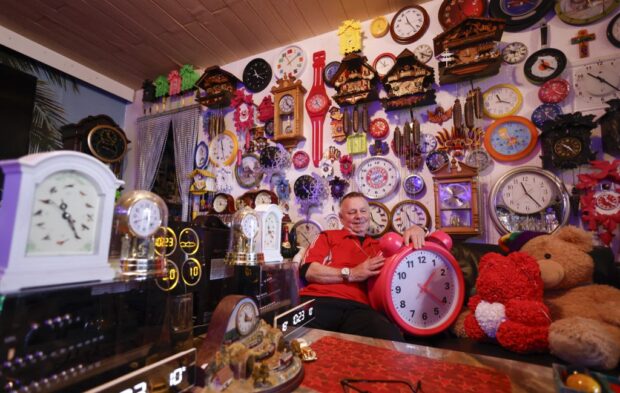 Werner Stechbarth poses inmid his collection of clocks 