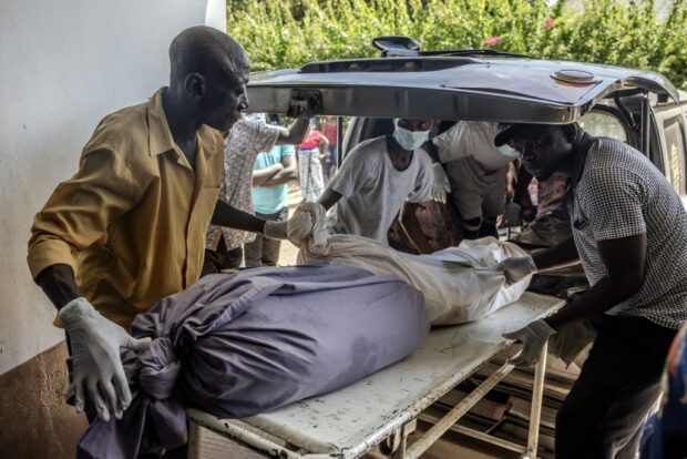Mortuary workers move the remains of several members of the same family who were victims of a Kenyan starvation cult 