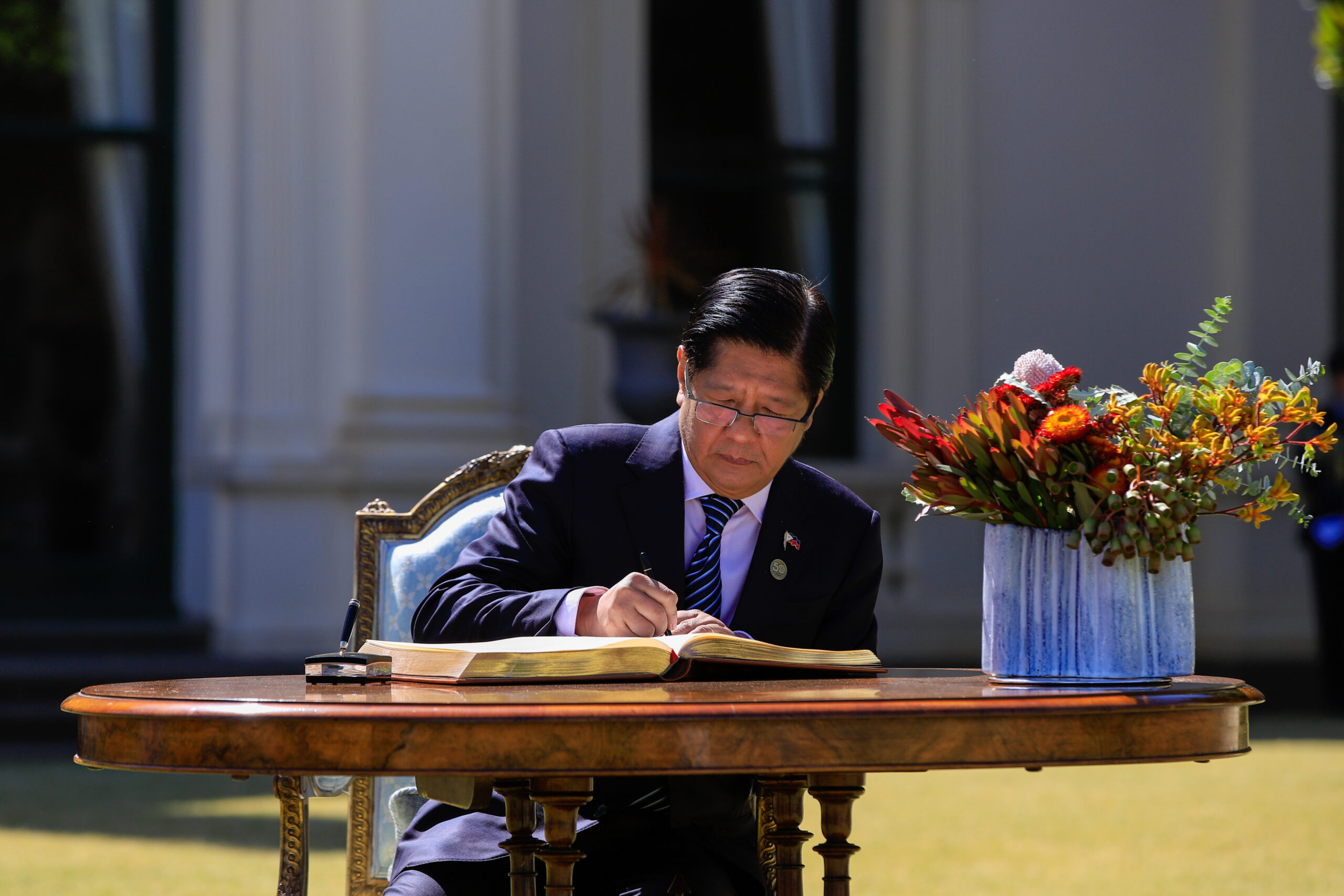 President Marcos, pictured signing a guestbook in Melbourne
