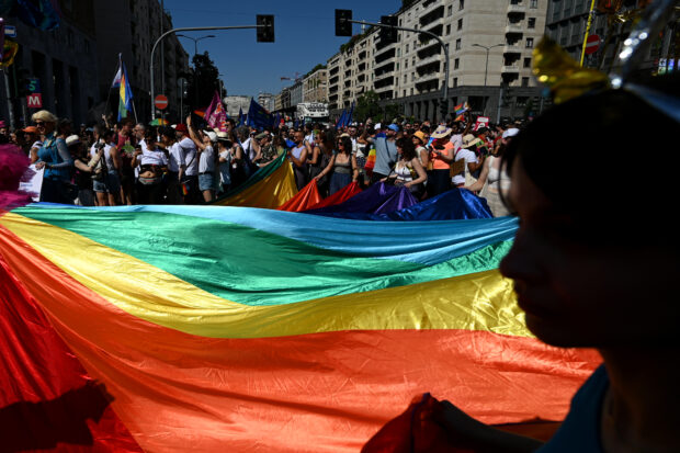 I partecipanti tengono una gigantesca bandiera arcobaleno mentre prendono parte a una parata del Pride per mostrare sostegno ai membri della comunità LGBT, a Milano il 24 giugno 2023. (Foto di GABRIEL BOUYS / AFP)