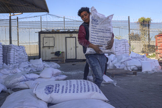A worker carries bags of humanitarian aid that entered Gaza by truck through the Kerem Shalom (Karm Abu Salem) border crossing in the southern part of the Palestinian territory on February 17, 2024, in Rafah on the southern Gaza Strip, amid the ongoing conflict between Israel and the Palestinian militant group Hamas.SAID KHATIB / AFP