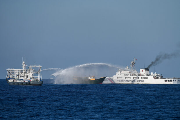 This photo taken on March 5, 2024 shows China Coast Guard vessels deploying water cannons at the Philippine military chartered Unaizah May 4 (C) during its supply mission to Second Thomas Shoal in the disputed South China Sea. The Philippines said on March 5 that China Coast Guard vessels caused two collisions with Philippine boats and water cannoned one of them, leaving four crew injured.