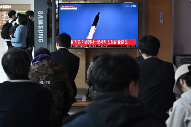 People watch a television screen showing a news broadcast with file footage of a North Korean missile test, at a railway station in Seoul on April 2, 2024. North Korea fired a medium-range ballistic missile on April 2, Seoul's military said, the latest in a spate of banned weapons tests by Kim Jong Un's regime this year. (Photo by Jung Yeon-je / AFP)