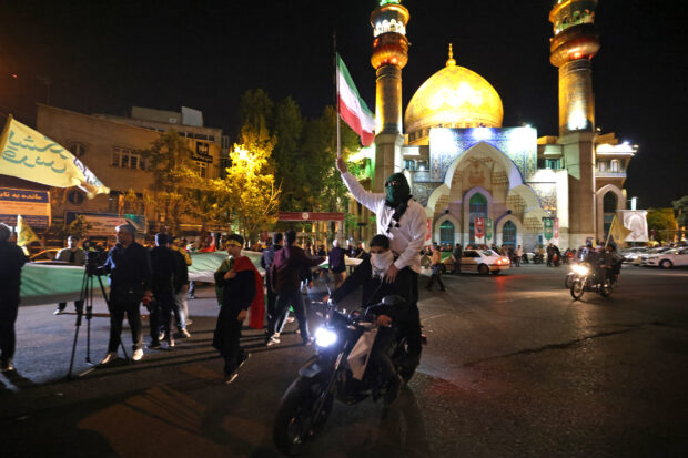 Demonstrators wave Iran's flag as they gather at Palestine Square in Tehran on April 14, 2024, after Iran launched a drone and missile attack on Israel. Iran's Revolutionary Guards confirmed early April 14, 2024 that a drone and missile attack was under way against Israel in retaliation for a deadly April 1 drone strike on its Damascus consulate.ATTA KENARE / AFP